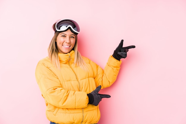 Jeune, caucasien, femme, porter, ski, vêtements, rose, mur, excité, pointage, index, loin