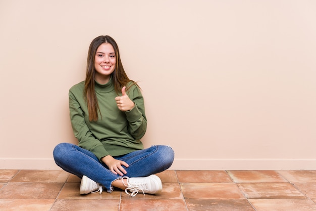 Jeune, caucasien, femme, séance terre, isolé, sourire, et, lever pouce haut