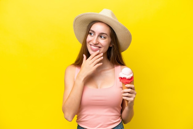 Jeune caucasien avec une glace au cornet isolé sur fond jaune levant les yeux en souriant