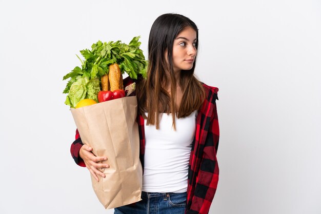 Jeune caucasien avec légumes isolé sur blanc à la recherche sur le côté