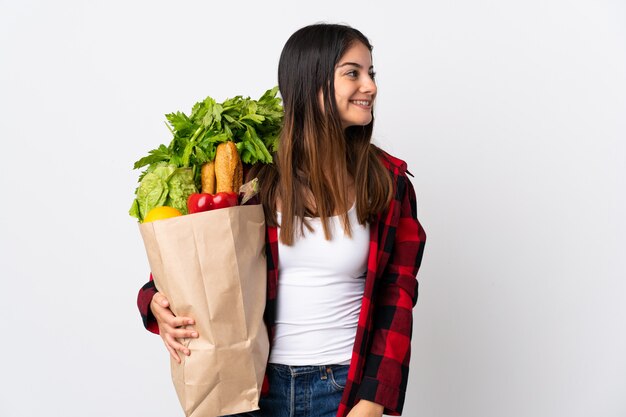 Jeune caucasien avec des légumes isolés sur blanc en riant en position latérale