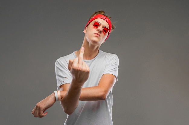 Jeune, caucasien, lunettes soleil rouges, t-shirt blanc, poser, sur, mur gris