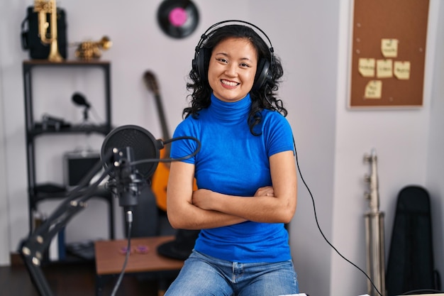 Jeune chanteuse chinoise souriante confiante avec les bras croisés geste au studio de musique