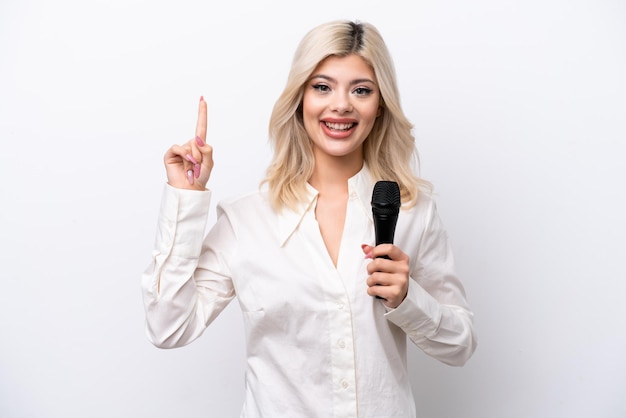 Jeune chanteuse femme prenant un microphone isolé sur fond blanc pointant vers le haut une excellente idée