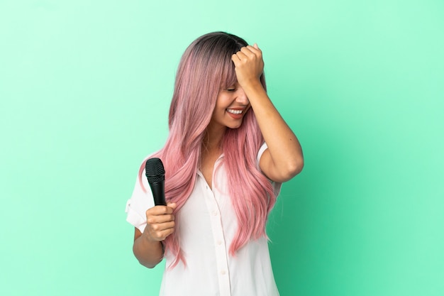 Une jeune chanteuse métisse aux cheveux roses isolée sur fond vert a réalisé quelque chose et envisage la solution