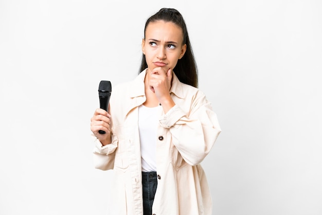 Jeune chanteuse prenant un microphone sur fond blanc isolé ayant des doutes