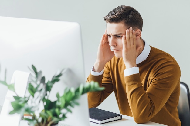 Jeune Et Charmant Homme D'affaires Pense Aux Affaires Alors Qu'il Est Assis Dans Son Bureau Moderne