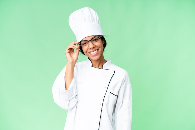 Jeune chef afro-américain sur un fond de clé chrome isolé avec des lunettes et heureux