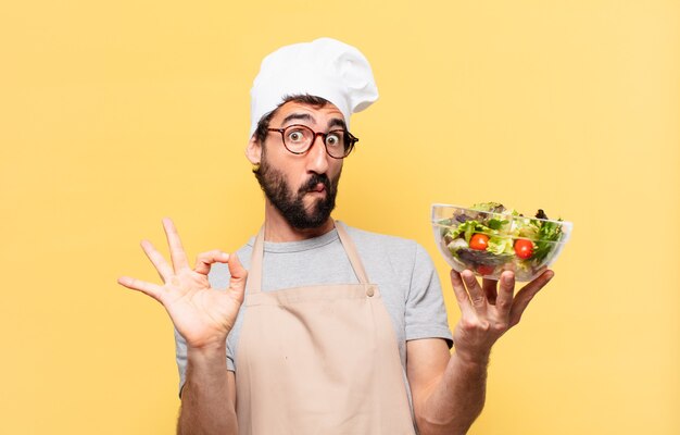 Jeune chef barbu homme surpris expression et tenant une salade