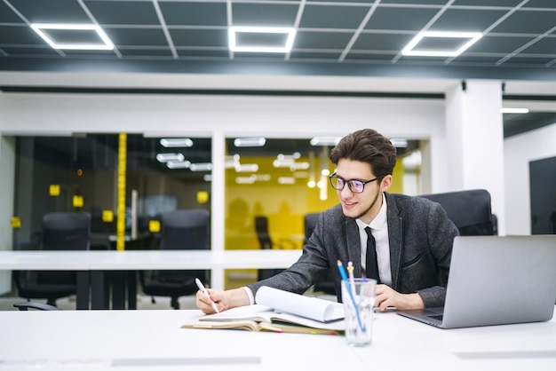 Jeune chef de bureau travaillant avec des papiers et un ordinateur au bureau Examiner et analyser des documents