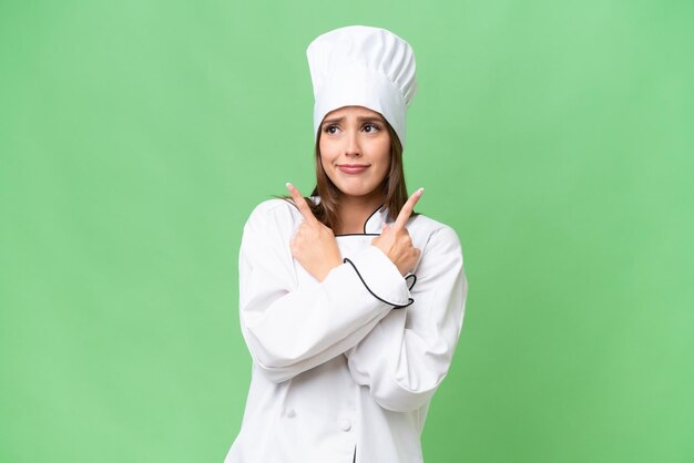 Jeune chef caucasien femme sur fond isolé pointant vers les latéraux ayant des doutes