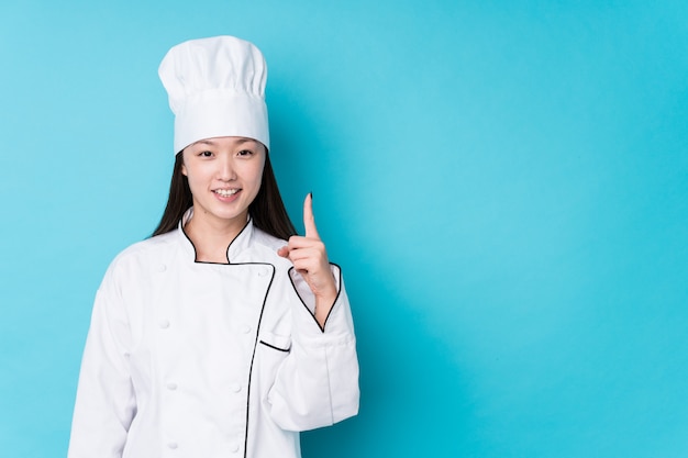 Jeune chef chinois femme isolée montrant le numéro un avec le doigt.