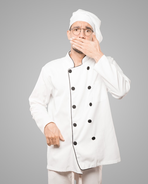 Jeune chef couvrant sa bouche avec ses mains