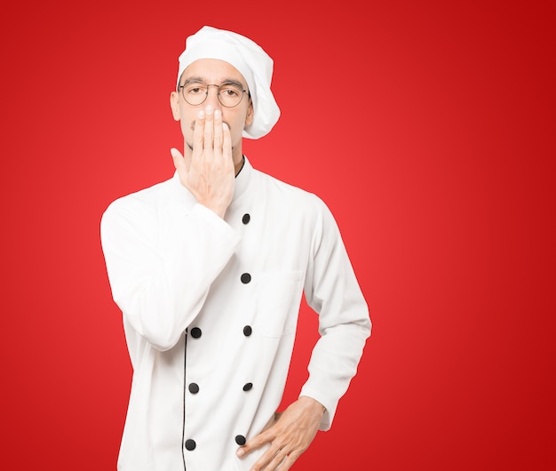 Jeune chef couvrant sa bouche avec ses mains