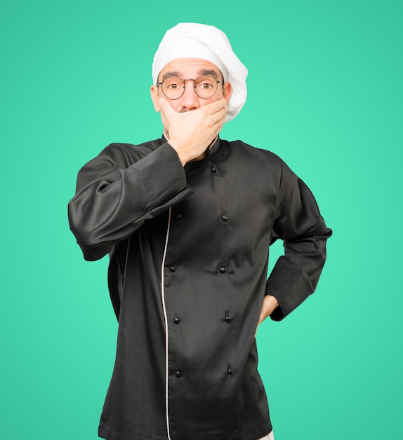 Jeune chef couvrant sa bouche avec ses mains