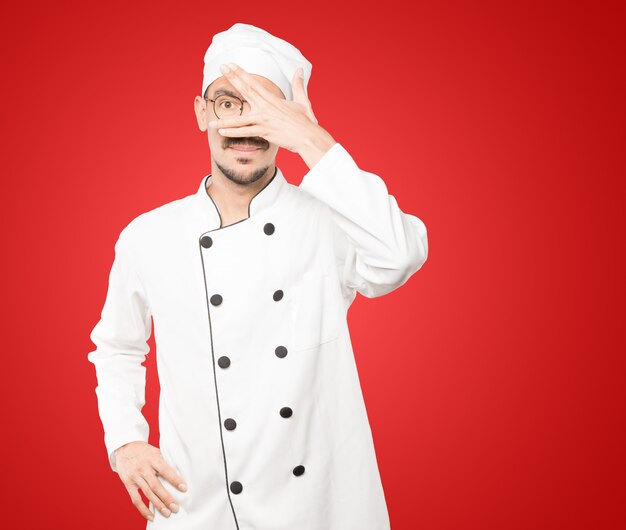 Jeune chef couvrant ses yeux avec ses mains