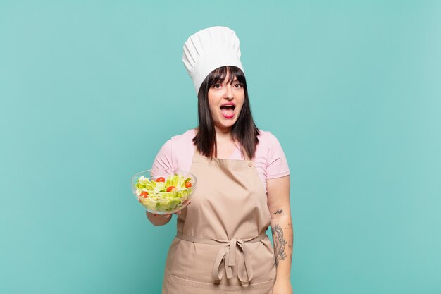 jeune chef femme à l'air heureuse et agréablement surprise, excitée par une expression fascinée et choquée