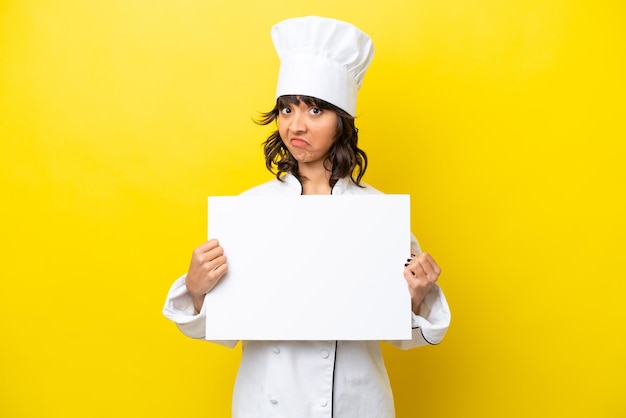 Jeune chef femme latine isolée sur fond jaune tenant une pancarte vide