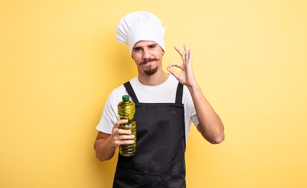 Jeune chef avec moustache avec bouteille d'huile d'olive