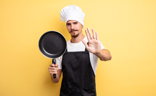 Jeune chef avec moustache et une casserole