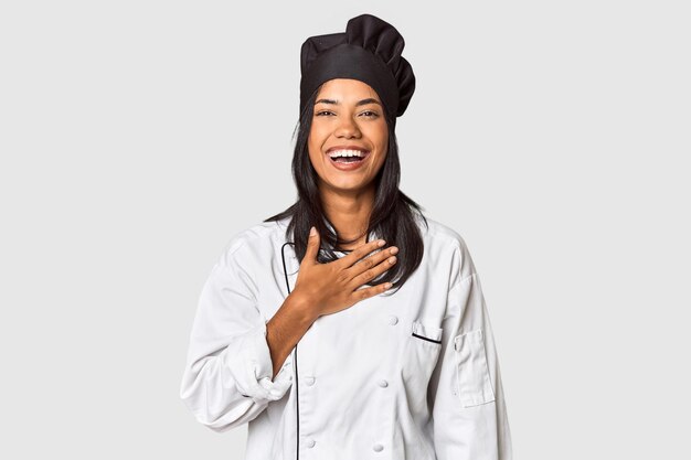 Photo un jeune chef philippin avec un chapeau de cuisine dans le studio rit fort en gardant la main sur la poitrine