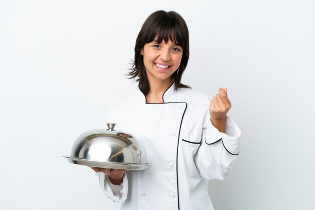 Jeune chef avec plateau isolé sur fond blanc faisant un geste d'argent