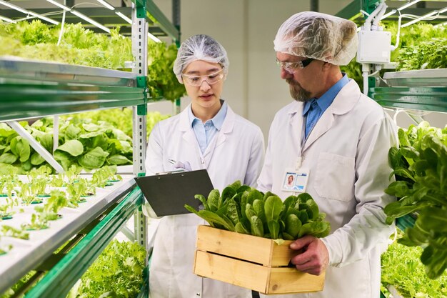 Jeune chercheuse prenant des notes dans un document tout en regardant des semis