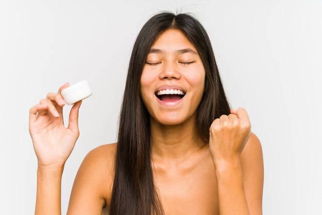 Jeune, chinois, femme, tenue, hydratant, isolé, applaudissement, insouciant, excité Concept de victoire.