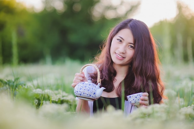 Jeune, chinois, girl, Verser, thé, fleurir, pré