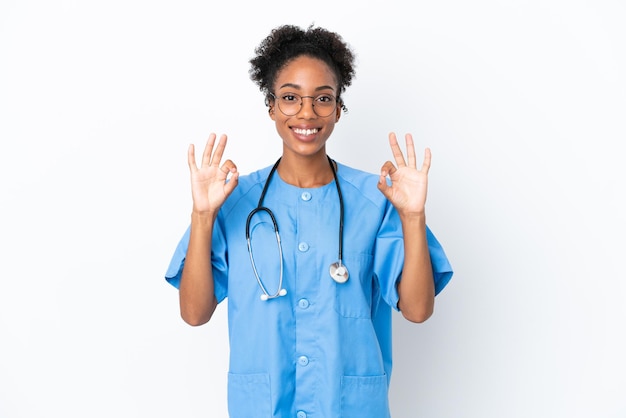 Jeune chirurgien femme médecin afro-américaine isolée sur fond blanc montrant un signe ok avec les doigts