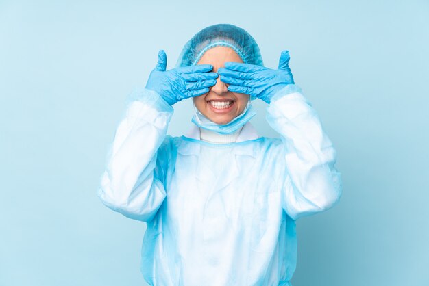 Jeune chirurgien femme en uniforme bleu couvrant les yeux par les mains