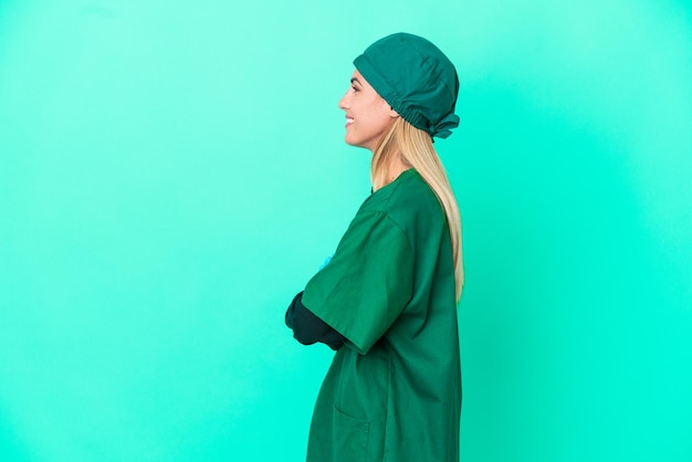 Jeune chirurgien femme uruguayenne en uniforme vert isolé sur fond bleu en position latérale