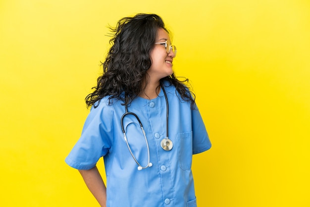 Jeune chirurgien médecin femme asiatique isolée sur fond jaune à côté
