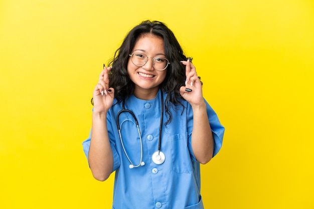 Jeune Chirurgien Médecin Femme Asiatique Isolée Sur Fond Jaune Avec Croisement De Doigts