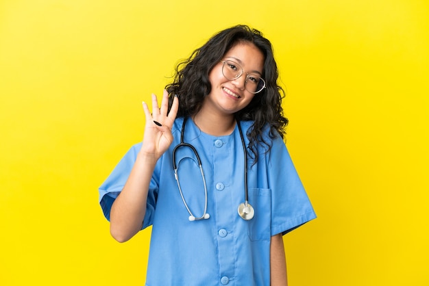 Jeune chirurgien médecin femme asiatique isolée sur fond jaune heureux et comptant quatre avec les doigts