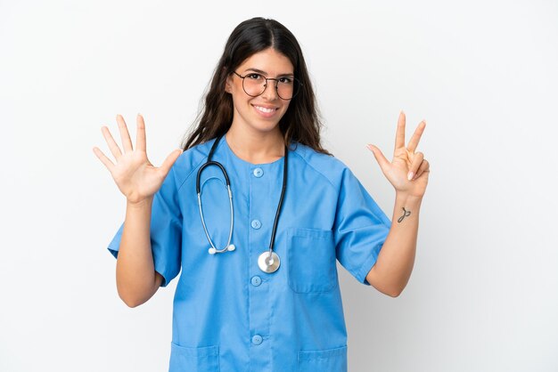 Jeune chirurgien médecin femme caucasienne isolée sur fond blanc comptant huit avec les doigts