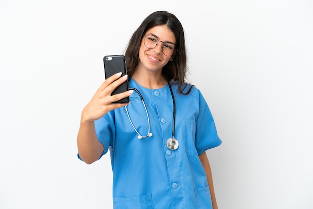 Jeune chirurgien médecin femme caucasienne isolée sur fond blanc faisant un selfie