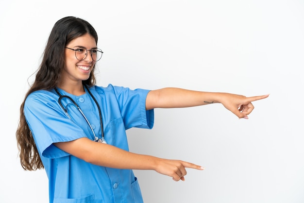 Jeune chirurgien médecin femme caucasienne isolée sur fond blanc, pointant le doigt sur le côté et présentant un produit