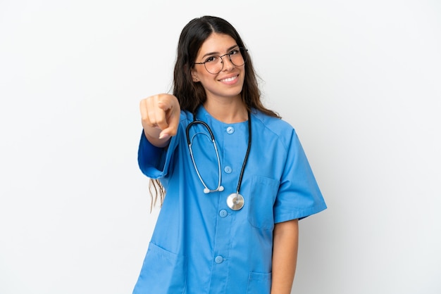 Jeune chirurgien médecin femme caucasienne isolée sur fond blanc pointe le doigt vers vous avec une expression confiante