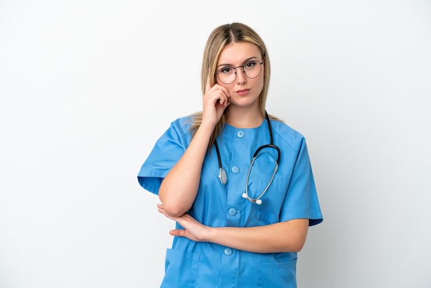 Jeune chirurgien médecin femme isolée sur fond blanc en pensant à une idée