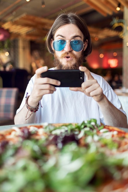 Un jeune client masculin surpris ne peut s'empêcher de faire et de partager la photo de la pizza servie