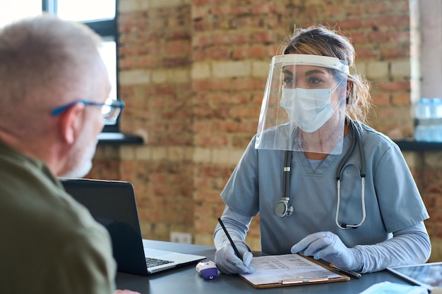 Jeune clinicienne écoutant un réfugié masculin mûr décrire ses symptômes