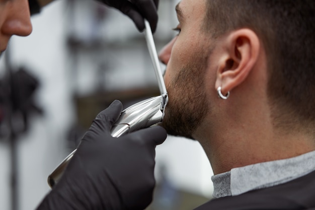 Jeune coiffeur coiffant la barbe d'un client