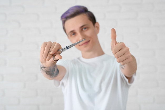 Jeune coiffeuse avec des cheveux lilas toniques, gesticulant à la caméra.