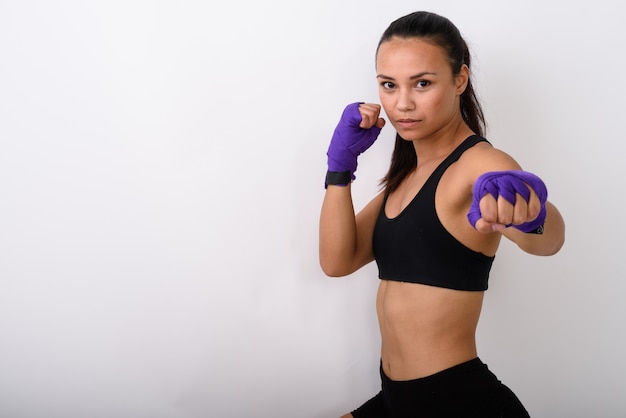 Jeune combattant de femme asiatique avec des enveloppes de boxe prêt à lutter contre l'espace blanc