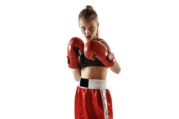 Jeune combattante de kickboxing posant confiante sur un mur blanc. Fille blonde caucasienne en vêtements de sport rouges pratiquant les arts martiaux. Concept de sport, mode de vie sain, mouvement, action, jeunesse.