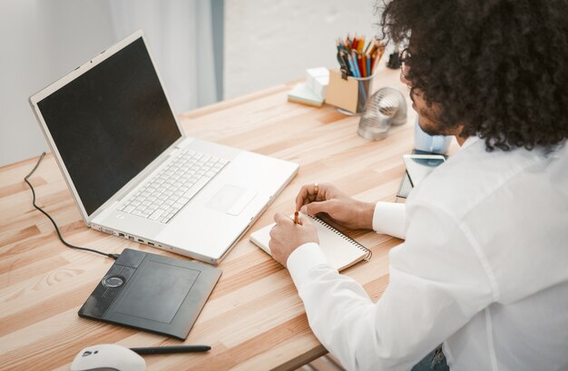 Jeune concepteur-rédacteur ou concepteur prend des notes dans un carnet de notes pour faire de futurs projets