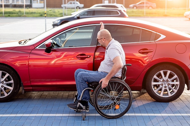 Jeune conducteur handicapé entrant dans une voiture rouge en fauteuil roulant