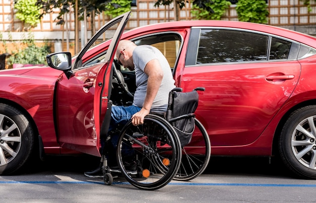 Jeune conducteur handicapé en voiture rouge en fauteuil roulant.