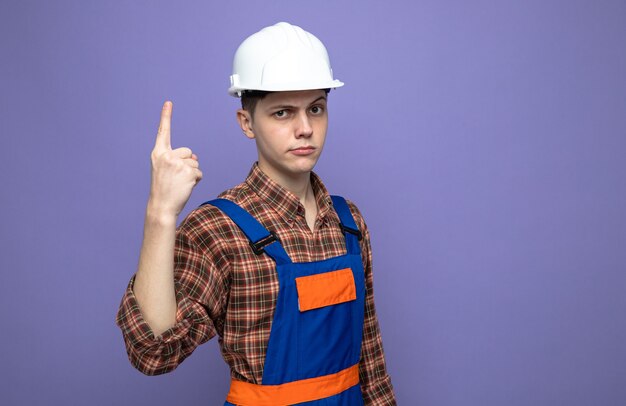 Jeune constructeur masculin en uniforme isolé sur mur violet